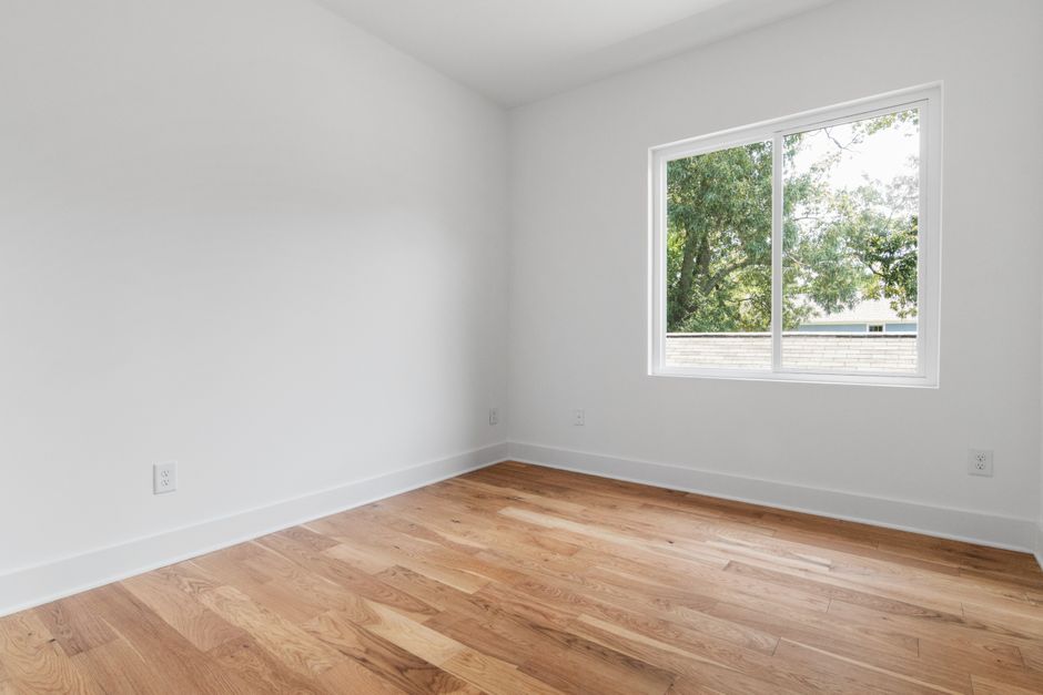 Empty living room with bare walls and hardwood floor before the design project